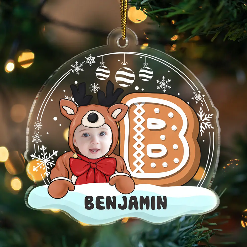 Christmas ornament with a child in a reindeer costume and gingerbread man design, set against a festive background.