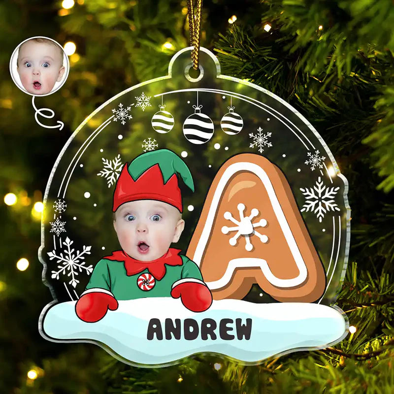 Christmas ornament with a child in an elf costume, gingerbread man, and snowflakes on a tree.